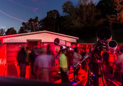 People gathered at Lookout Observatory with a telescope at night